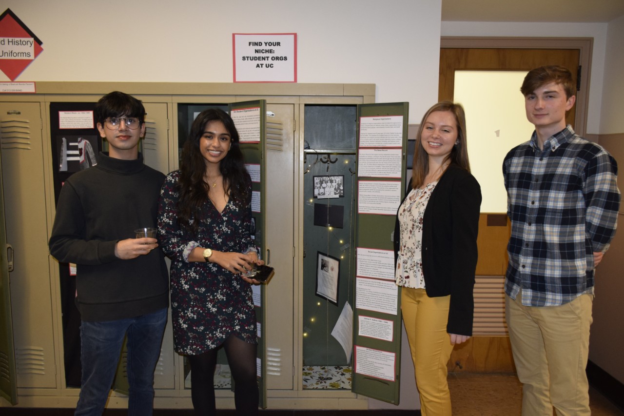 Four students standing in front of locker exhibits