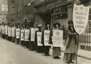 Black and white photo of women suffragettes in a line with signs