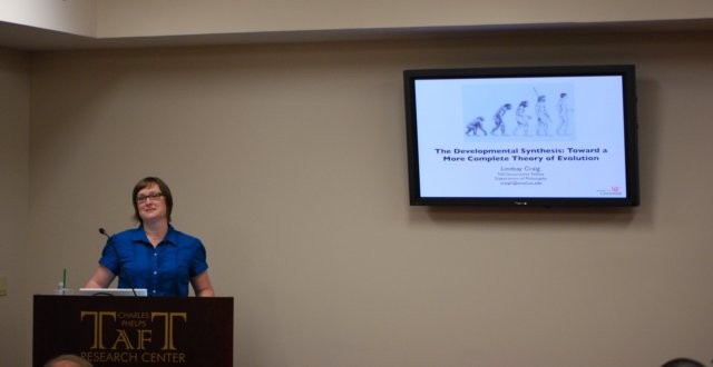 A person speaking with a powerpoint slide on screen