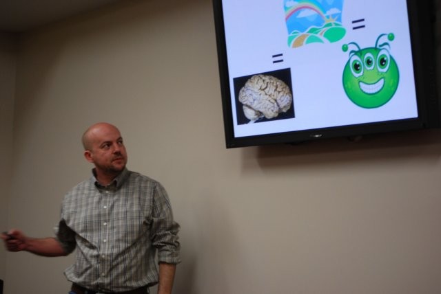 A person speaking with a powerpoint slide on screen