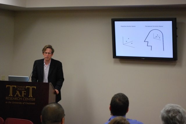 A person speaking with a powerpoint slide on screen