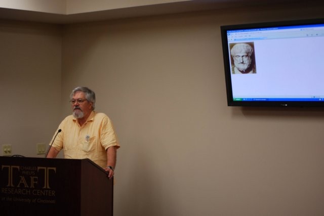 A person speaking with a powerpoint slide on screen