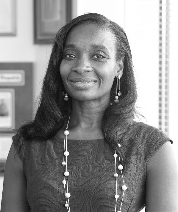 A black-and-white photograph of Dr. Gymama Slaughter wearing a dress, earrings, and a necklace.