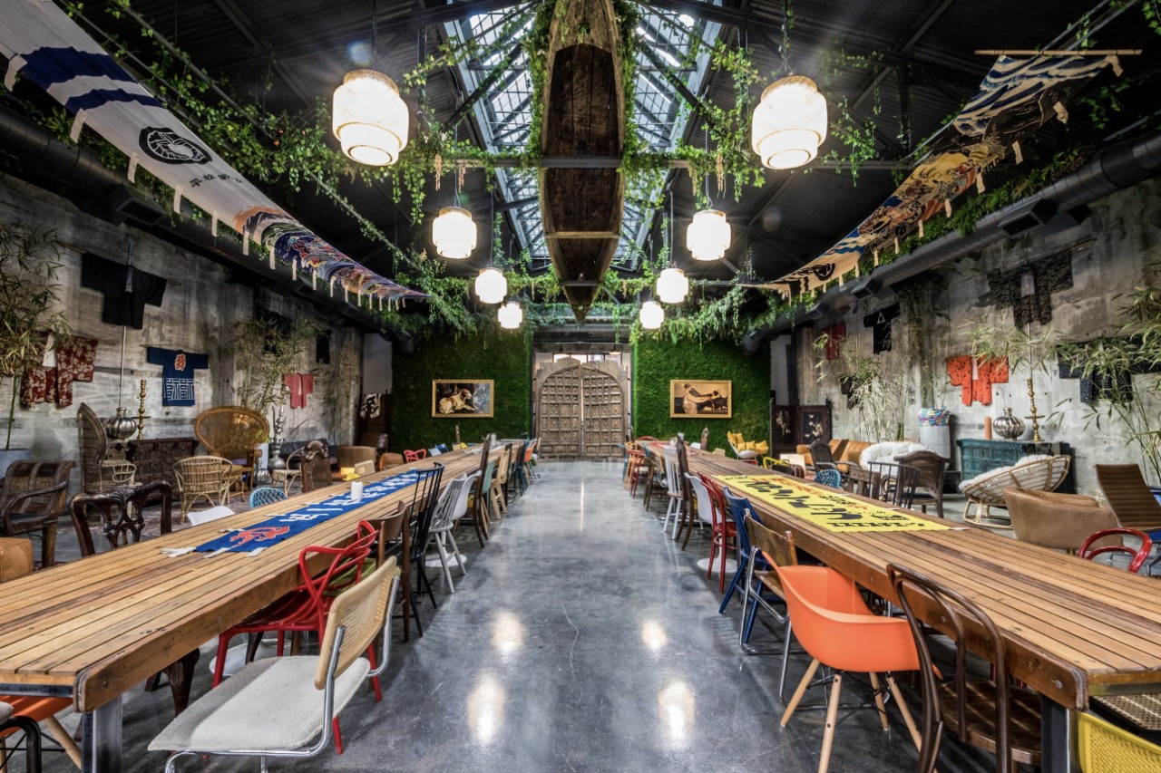 A photograph of the Somerhaus event space, decorated with long tables, a longboat hanging on the ceiling, and decorate lights and greenery.