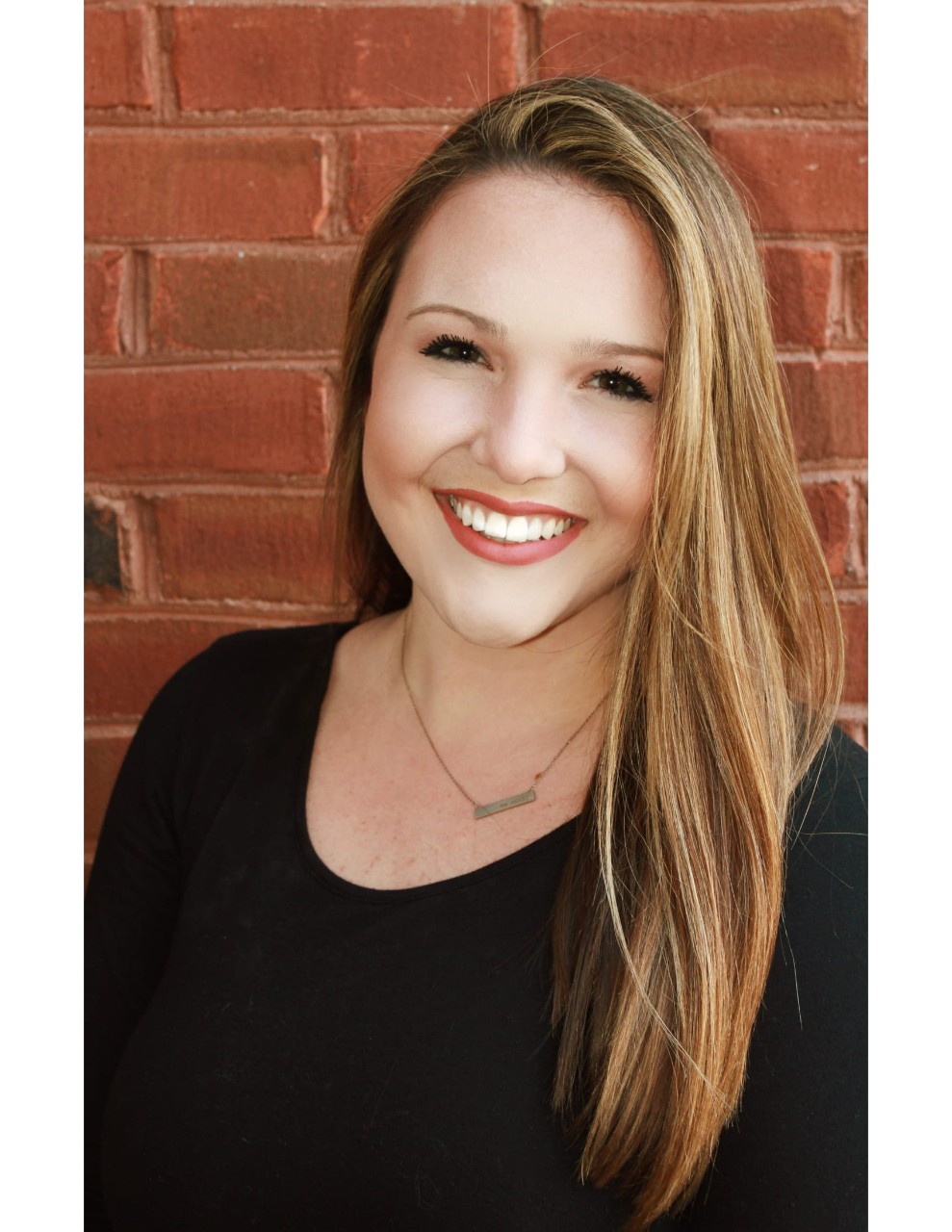 Portrait of Emily Godar outside against a brick wall