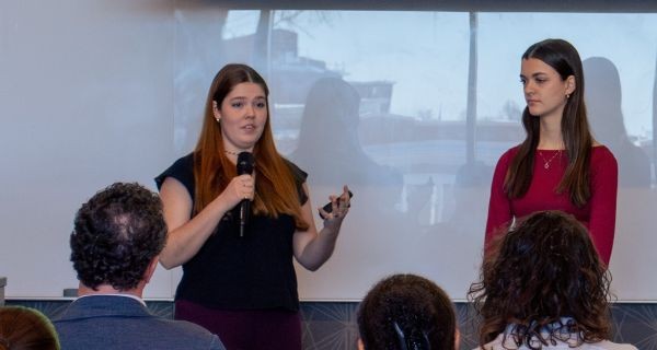 Student speaks into microphone in front of seated audience