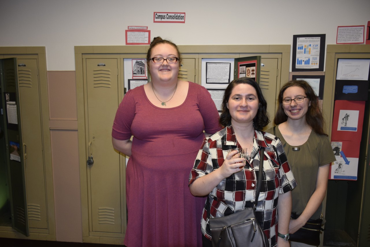 Three students standing in front of locker exhibits
