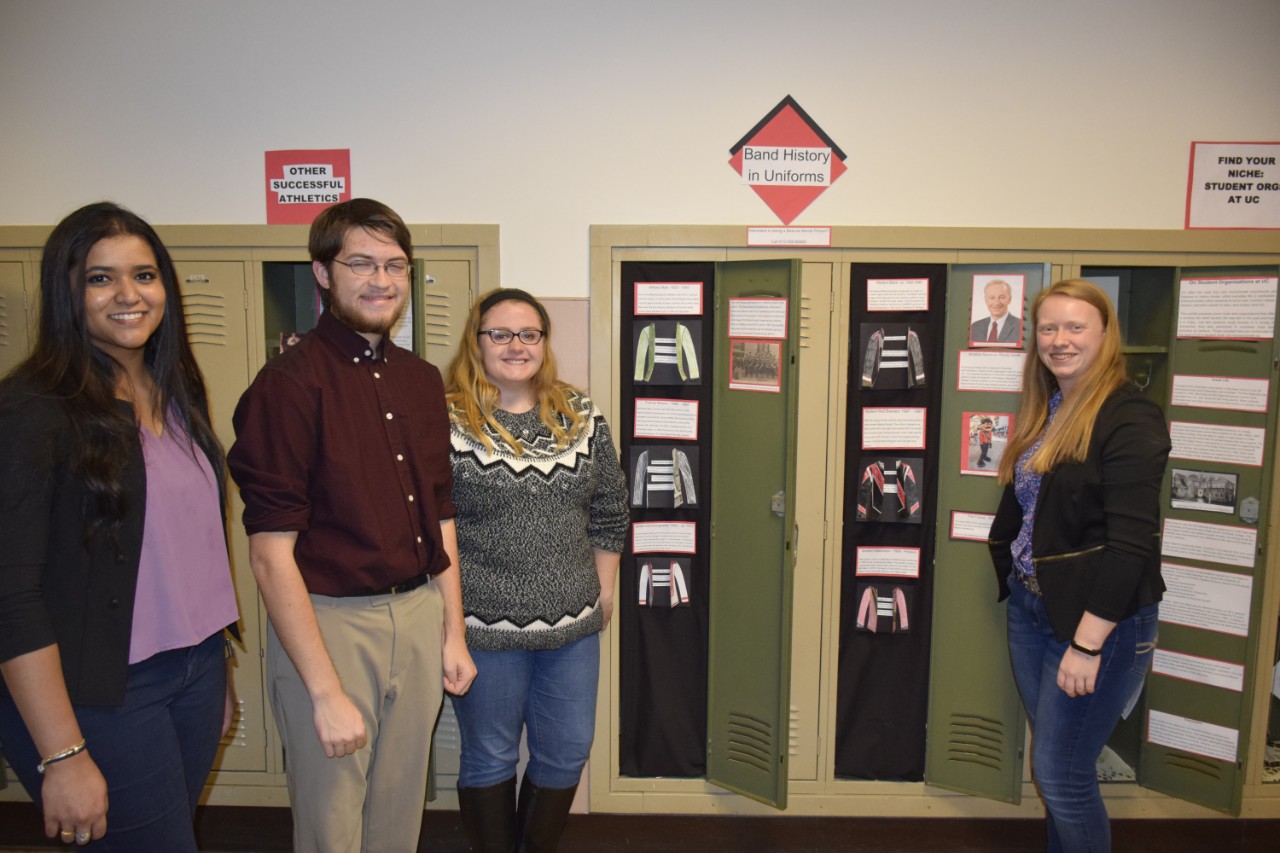 Four students standing in front of locker exhibits