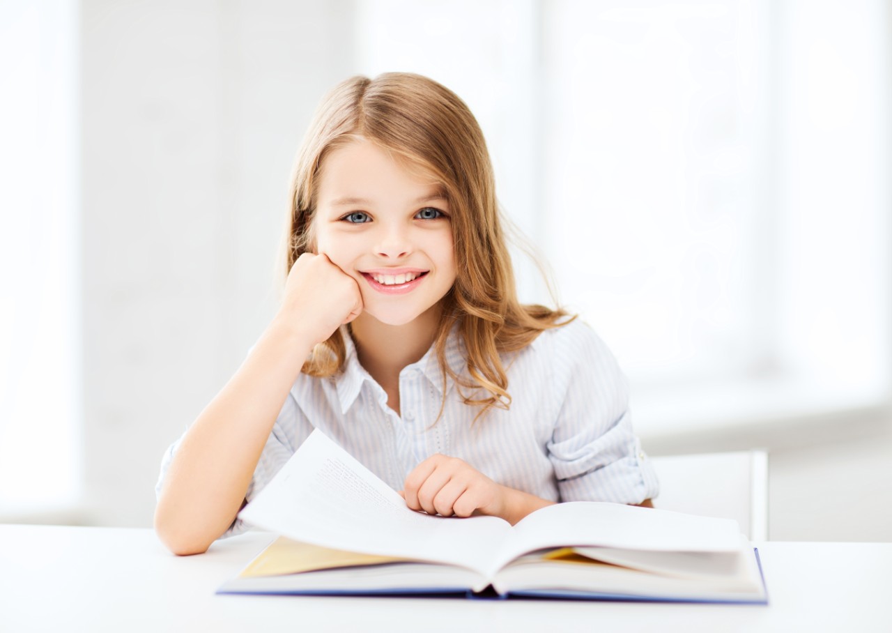Child looking up from book smiling
